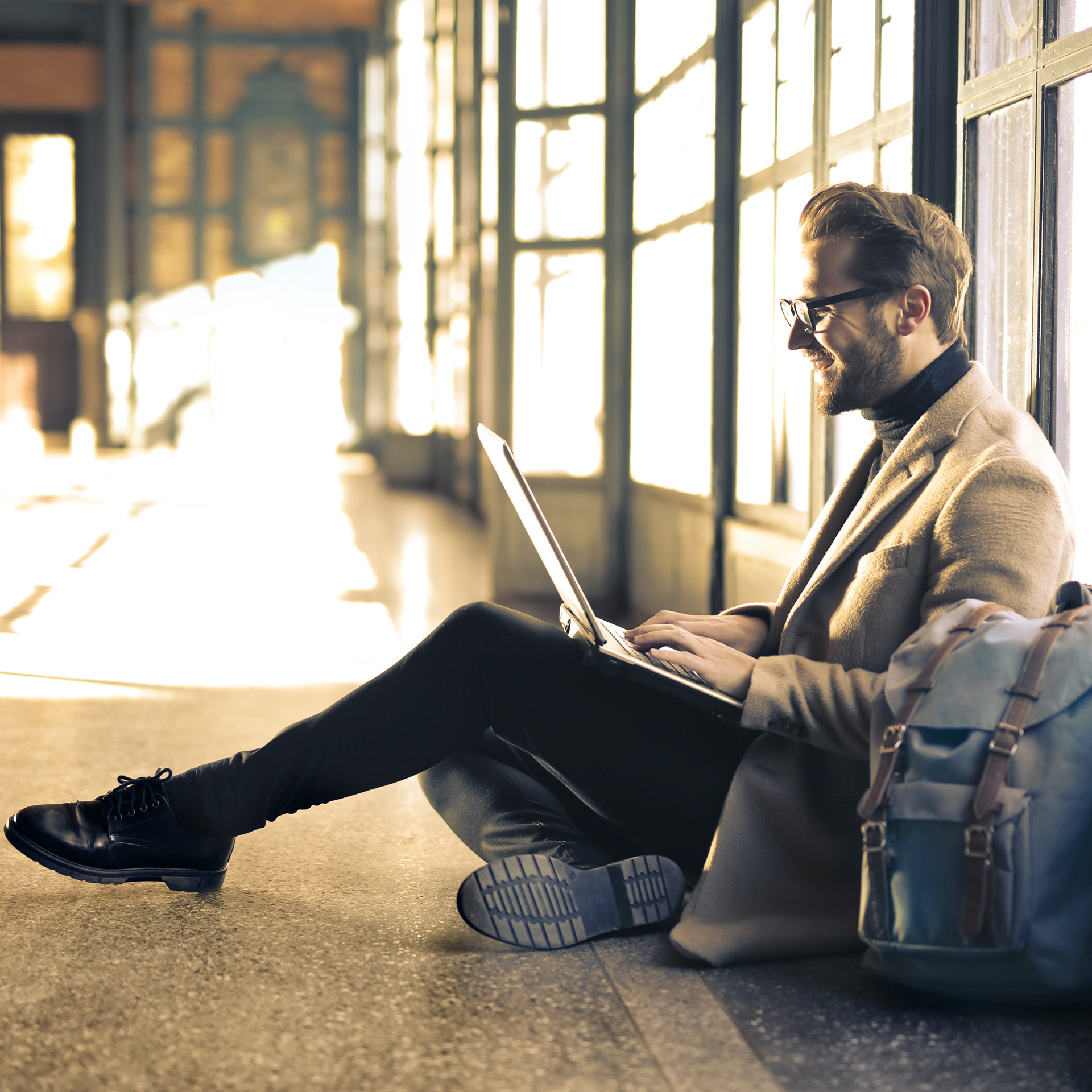 A man sitting in the hallway looking at his computer